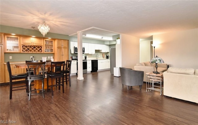 dining room with a textured ceiling, indoor bar, dark hardwood / wood-style floors, and an inviting chandelier