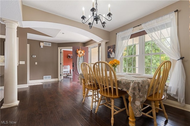 dining room with dark hardwood / wood-style flooring, ornate columns, and an inviting chandelier