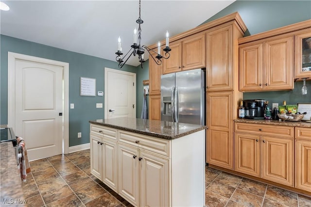 kitchen with stainless steel refrigerator with ice dispenser, dark stone counters, pendant lighting, a notable chandelier, and a kitchen island