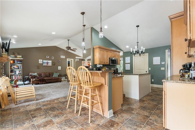 kitchen with ceiling fan with notable chandelier, kitchen peninsula, appliances with stainless steel finishes, and vaulted ceiling