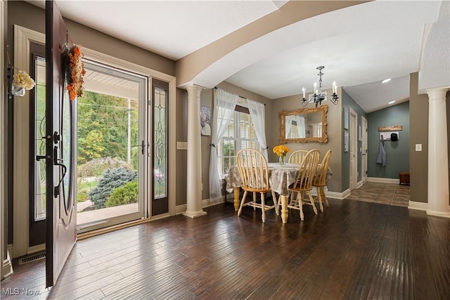 dining area with vaulted ceiling, ornate columns, dark wood-type flooring, and a chandelier