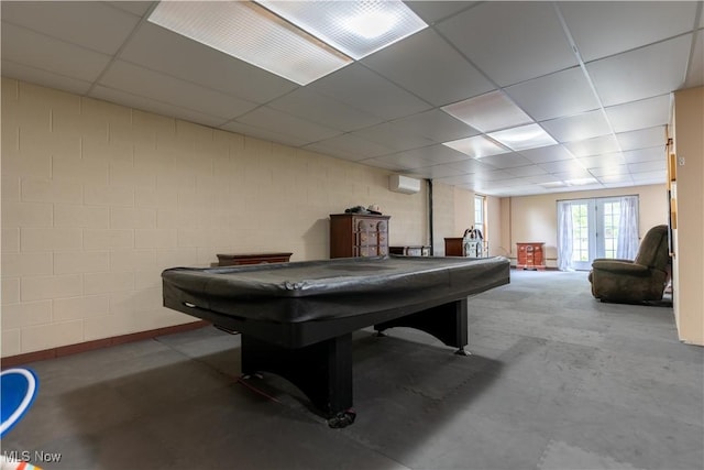 game room featuring a drop ceiling, french doors, an AC wall unit, pool table, and concrete flooring