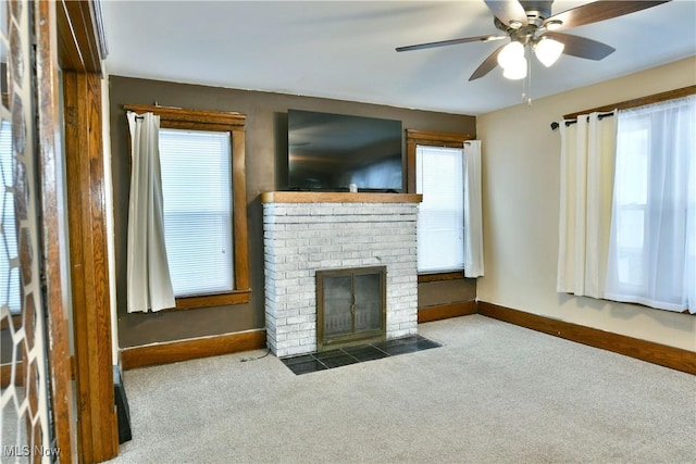 unfurnished living room with dark carpet, a brick fireplace, and ceiling fan