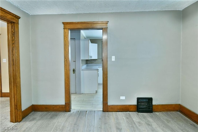 empty room with light wood-type flooring and a textured ceiling