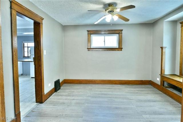 empty room with ceiling fan, light hardwood / wood-style floors, and a textured ceiling