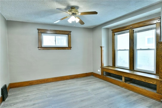 spare room with ceiling fan, plenty of natural light, light hardwood / wood-style floors, and a textured ceiling