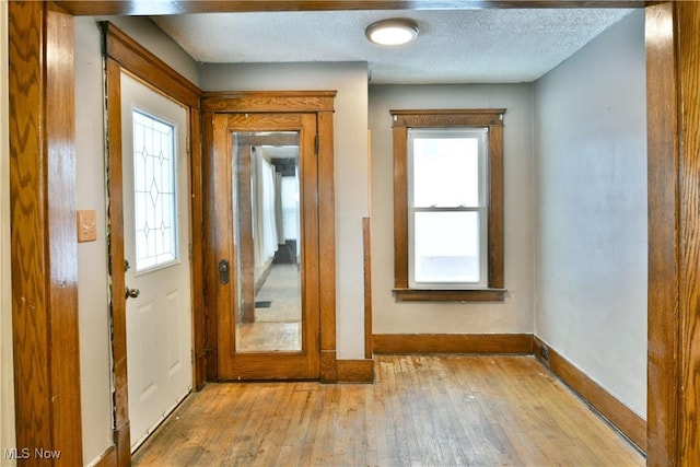 entryway with plenty of natural light, light hardwood / wood-style floors, and a textured ceiling