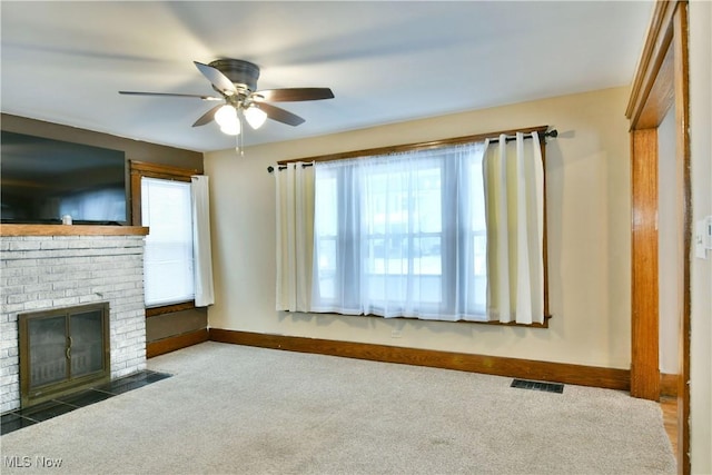 unfurnished living room with ceiling fan, dark carpet, and a brick fireplace