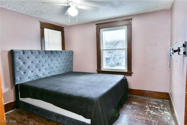 bedroom with a textured ceiling, ceiling fan, and dark wood-type flooring