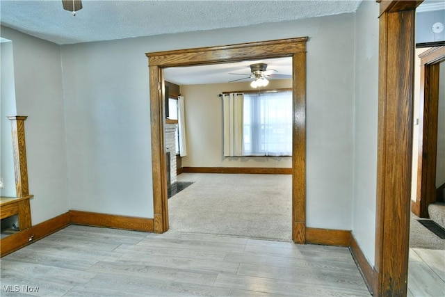 corridor featuring a textured ceiling and light wood-type flooring