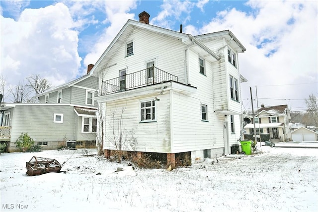 snow covered property with a balcony and central AC