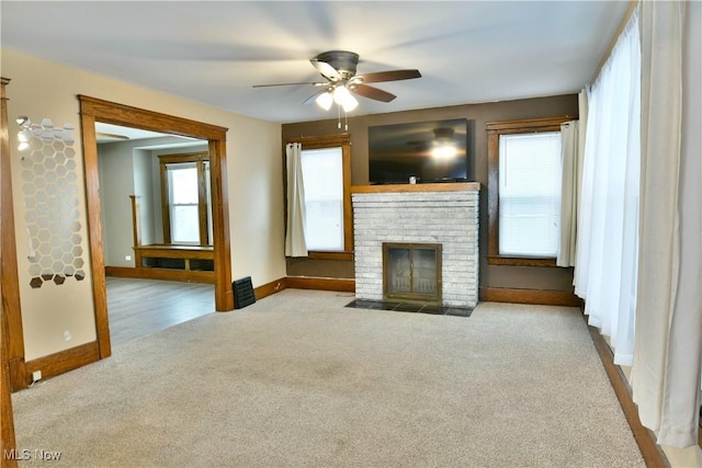 unfurnished living room with light carpet, ceiling fan, and a brick fireplace