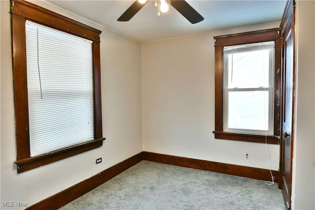 empty room with ceiling fan, light colored carpet, and a wealth of natural light