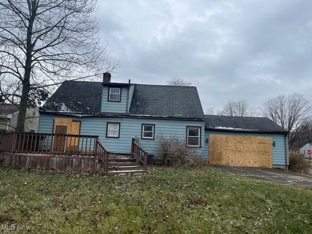 back of house with a garage and a lawn