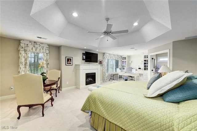 carpeted bedroom featuring ceiling fan and a tray ceiling