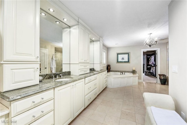 bathroom with a chandelier, vanity, tile patterned floors, and a bathtub