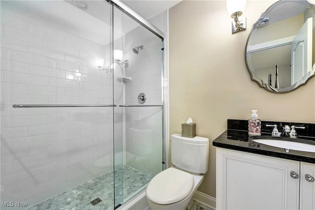 bathroom with vanity, a shower with shower door, and toilet