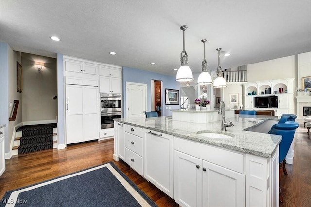 kitchen with a large island, white cabinets, pendant lighting, and dark hardwood / wood-style floors