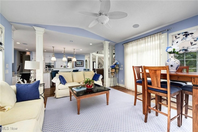 living room featuring ceiling fan, light wood-type flooring, ornate columns, and vaulted ceiling