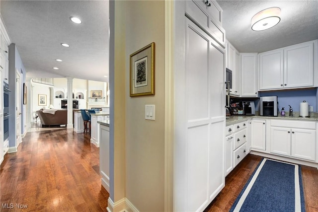 kitchen with a textured ceiling, white cabinetry, and dark wood-type flooring