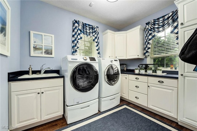 laundry area with sink, dark wood-type flooring, cabinets, a textured ceiling, and washer and clothes dryer