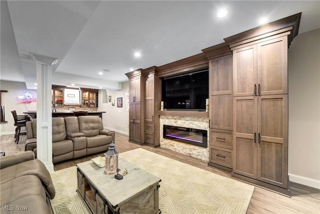 living room featuring a fireplace, light hardwood / wood-style flooring, and ornate columns