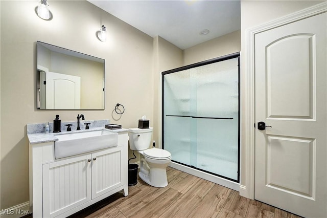 bathroom featuring toilet, vanity, an enclosed shower, and hardwood / wood-style flooring