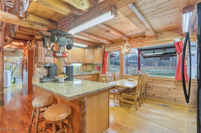 kitchen with wood walls, beam ceiling, wood ceiling, and light hardwood / wood-style flooring