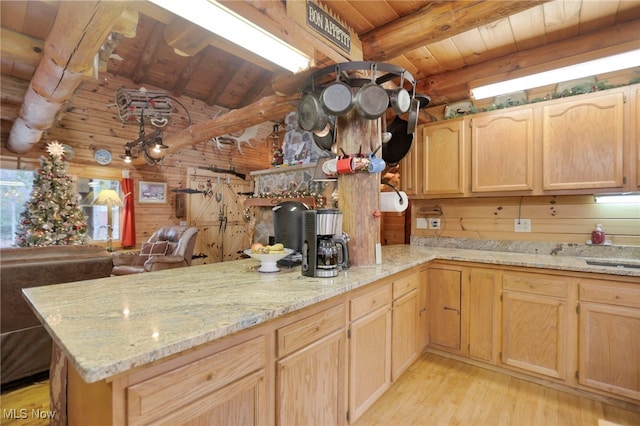 kitchen featuring wooden walls, light hardwood / wood-style flooring, light brown cabinetry, beamed ceiling, and kitchen peninsula