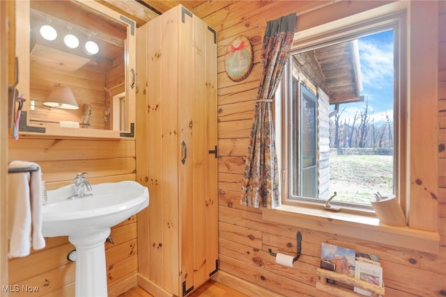 bathroom with wood ceiling, wood walls, and a healthy amount of sunlight