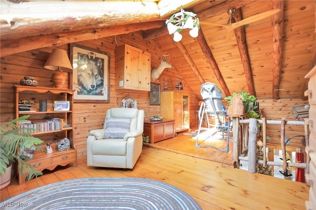 living area with vaulted ceiling with beams, wood walls, and light hardwood / wood-style flooring