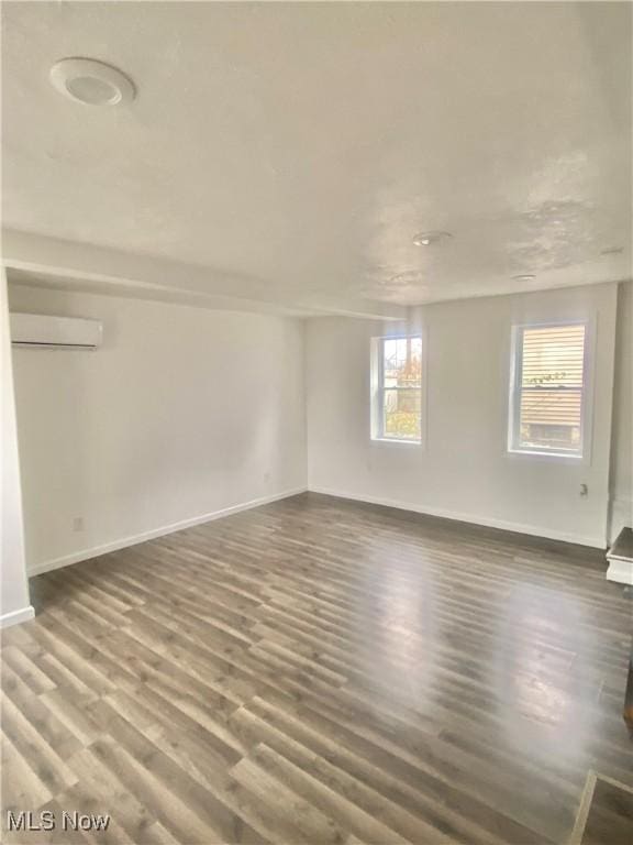 empty room with dark hardwood / wood-style flooring and an AC wall unit