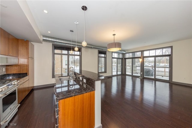 kitchen with sink, dark wood-type flooring, hanging light fixtures, and stainless steel range with gas stovetop