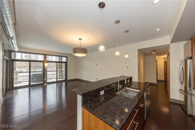 kitchen featuring a kitchen island with sink, sink, hanging light fixtures, dark hardwood / wood-style floors, and stainless steel appliances