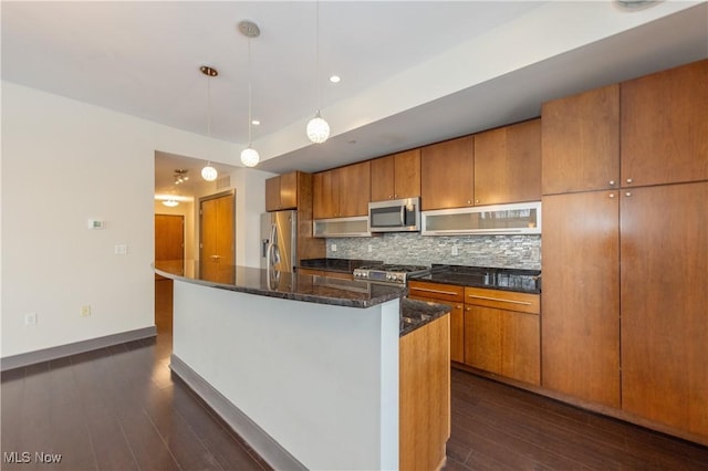 kitchen featuring appliances with stainless steel finishes, dark hardwood / wood-style flooring, a kitchen island with sink, and pendant lighting