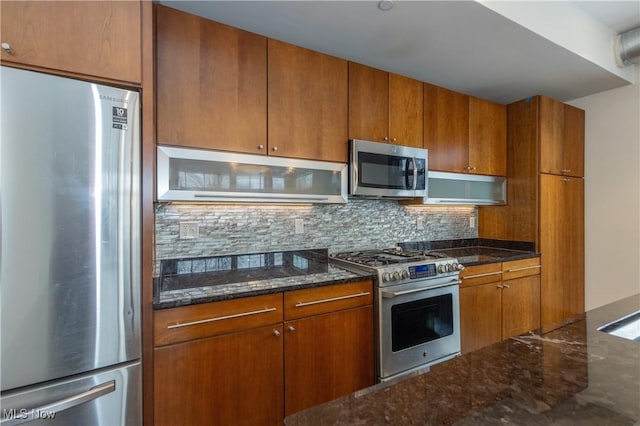 kitchen with backsplash, stainless steel appliances, dark stone countertops, and range hood