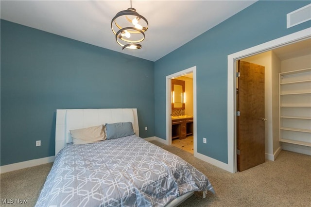 bedroom with a chandelier, ensuite bathroom, and light colored carpet