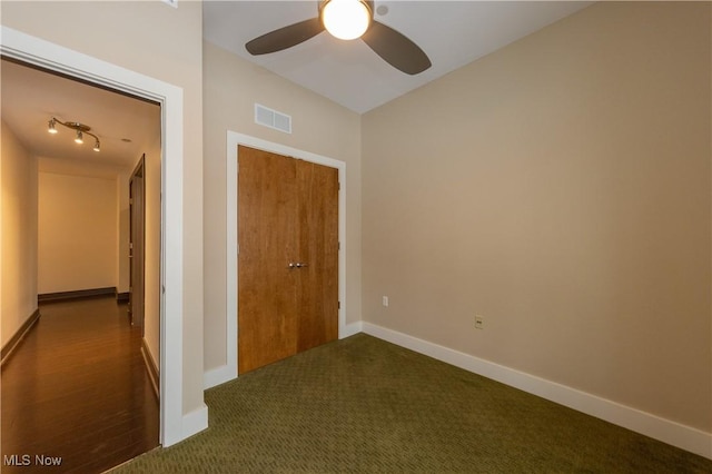 unfurnished bedroom with ceiling fan, a closet, and dark carpet