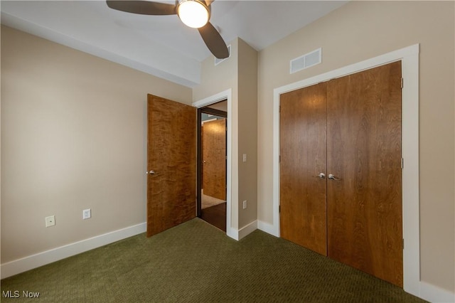 unfurnished bedroom featuring ceiling fan, a closet, and dark colored carpet