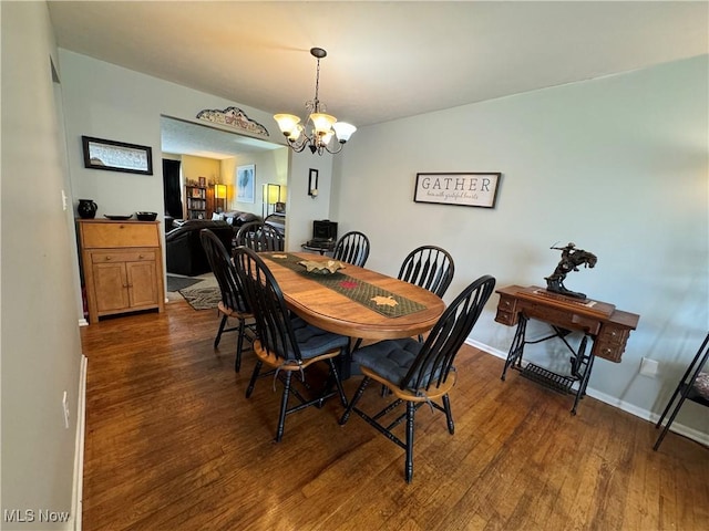 dining space featuring dark hardwood / wood-style floors and an inviting chandelier