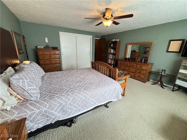 bedroom featuring carpet flooring, a textured ceiling, a closet, and ceiling fan