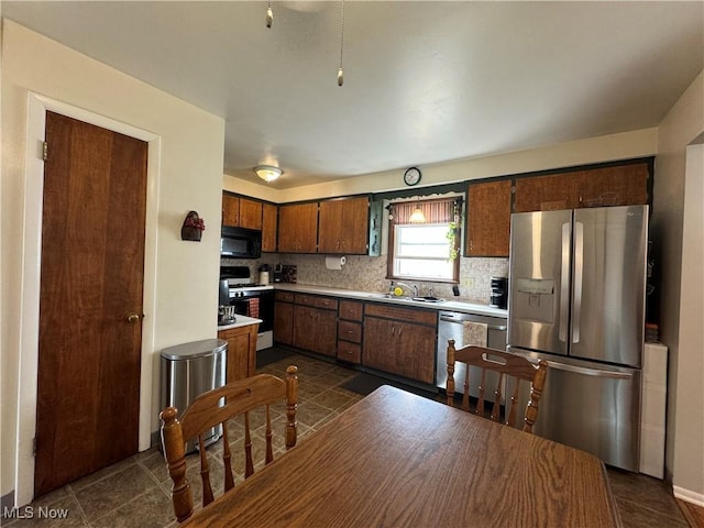 kitchen featuring decorative backsplash, dark tile patterned floors, and appliances with stainless steel finishes