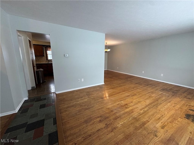 empty room featuring a notable chandelier and dark wood-type flooring