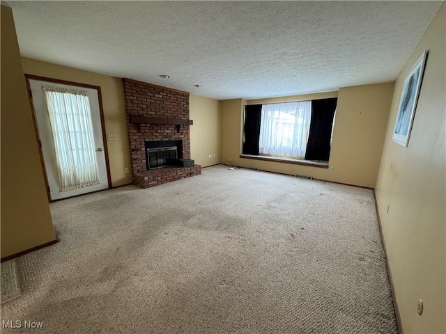 unfurnished living room featuring a wealth of natural light, a fireplace, light colored carpet, and a textured ceiling