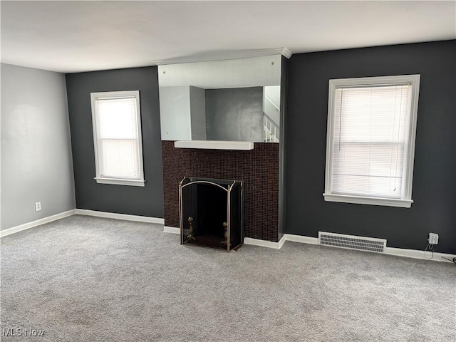 unfurnished living room with carpet floors and plenty of natural light