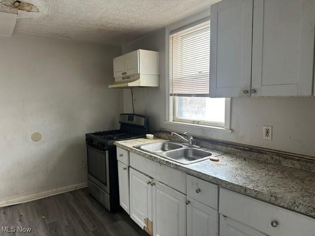 kitchen featuring gas stove, white cabinetry, sink, dark wood-type flooring, and a textured ceiling