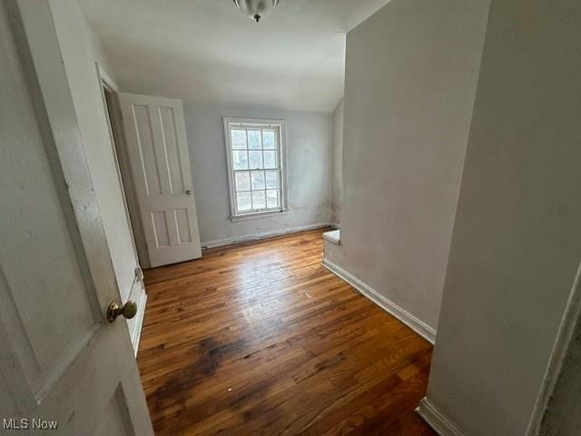 spare room featuring dark wood-type flooring and vaulted ceiling