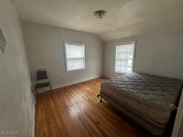 bedroom with hardwood / wood-style flooring, vaulted ceiling, and multiple windows