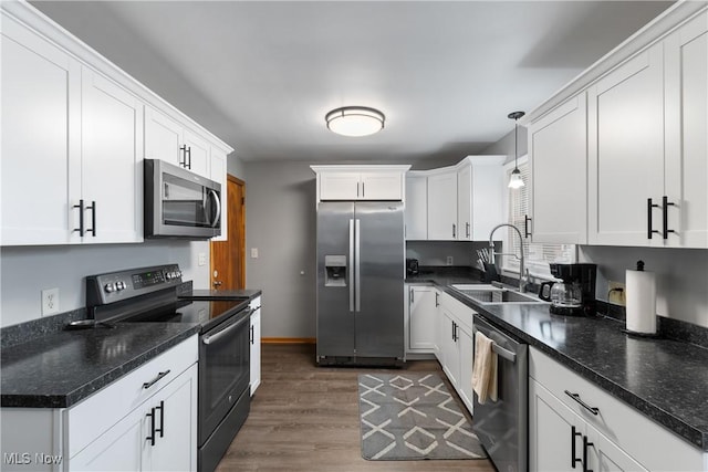 kitchen featuring sink, white cabinets, decorative light fixtures, and appliances with stainless steel finishes