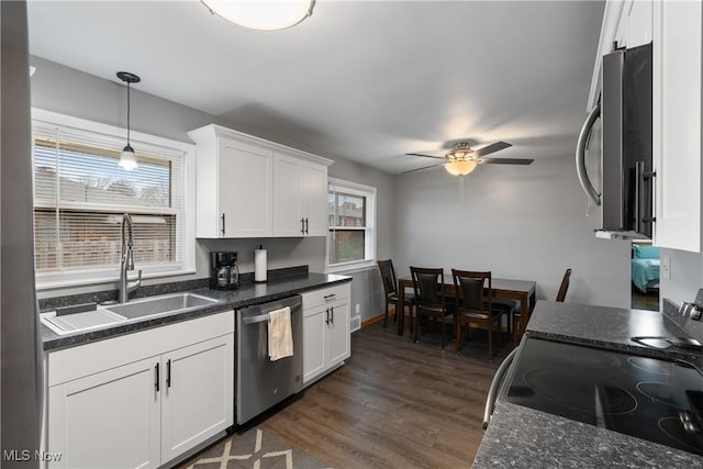 kitchen featuring dark wood-type flooring, white cabinets, hanging light fixtures, sink, and appliances with stainless steel finishes